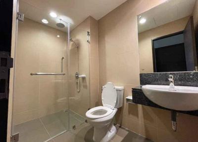 Modern bathroom with beige tiles, shower cabin, toilet, and sink