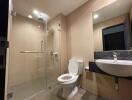 Modern bathroom with beige tiles, shower cabin, toilet, and sink