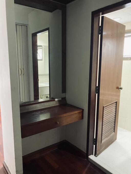 Entrance area with wooden dresser and mirror leading to a bathroom