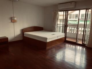 Spacious bedroom with wooden flooring and natural light