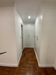 Brightly lit hallway with wooden flooring and white doors