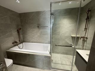 Modern bathroom with a well-lit interior featuring a bathtub and glass shower enclosure