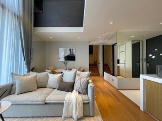 Modern living room with sofa, staircase and neutral color palette