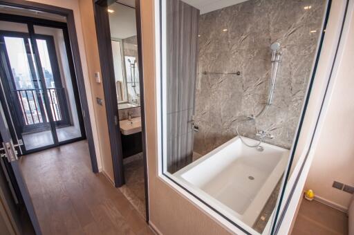 Modern bathroom with marble walls, glass shower enclosure, and direct access to balcony