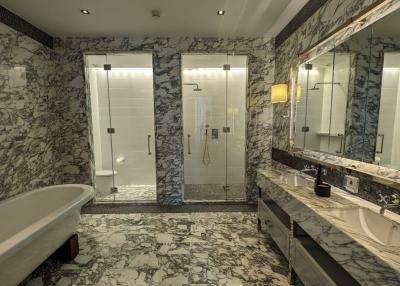 Spacious bathroom with marble tiles, oversized mirror, and glass shower