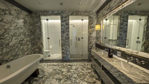 Spacious bathroom with marble tiles, oversized mirror, and glass shower