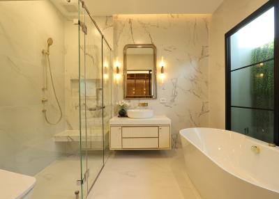 Modern bathroom with marble walls, glass shower, and bathtub
