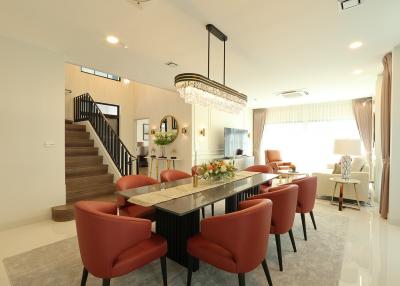 Spacious and well-lit living room with an elegant dining area, charming staircase, and modern decor