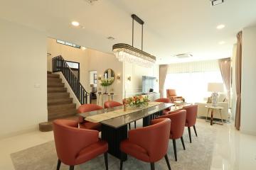 Spacious and well-lit living room with an elegant dining area, charming staircase, and modern decor