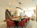 Spacious and well-lit living room with an elegant dining area, charming staircase, and modern decor