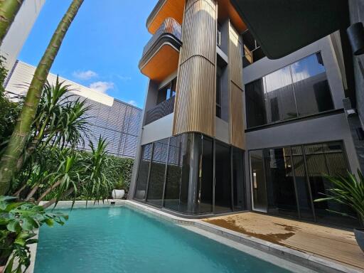 Modern house with a private pool and wooden deck surrounded by tropical plants