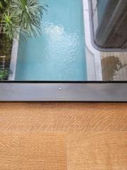 Partial view of a swimming pool and hardwood floor from a high angle