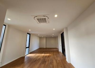 Spacious and well-lit empty living room with hardwood flooring and large windows