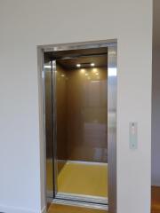 Residential elevator with open doors showing interior cabin lights