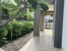 Paved walkway leading to a modern house with green landscaping