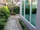 Paved pathway leading to a modern home with a green lawn and large windows