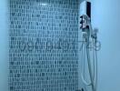 Modern bathroom with wall-mounted electric shower and blue mosaic tiles