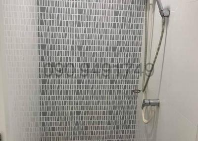 Modern tiled shower with glass door and handheld showerhead