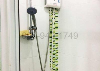 Wall-mounted water heater with a hand-held showerhead in a tiled bathroom