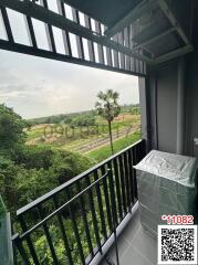 Balcony with a view of green fields and a metal railing