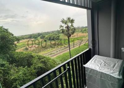 Balcony with a view of green fields and a metal railing