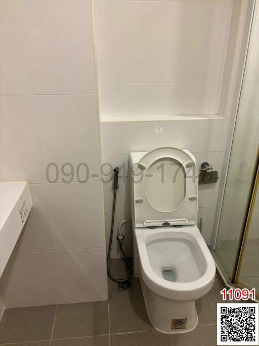 Modern white tiled bathroom with toilet and bidet shower