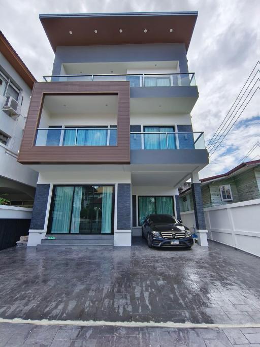 Modern multi-story residential building with balconies and a car parked in front