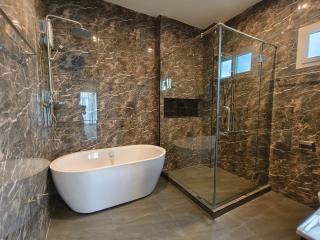 Modern bathroom with marble tiles, freestanding bathtub, and glass shower enclosure