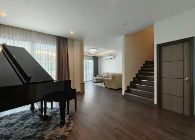 Spacious living room interior with a grand piano and staircase
