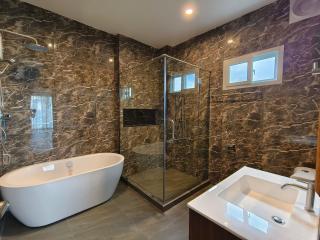 Modern bathroom with marble tiles, a freestanding bathtub, glass shower, and stylish fixtures