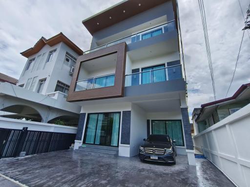 Modern multi-story residential building with a car parked in the driveway under a clear sky