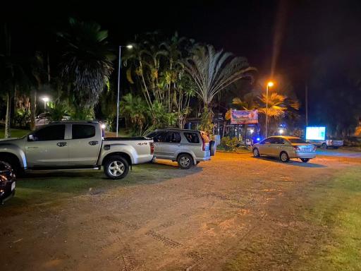 Night View of Property Exterior with Parked Cars and Lit Palm Trees