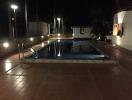 Illuminated outdoor pool area with seating during nighttime