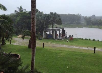 Rainy view of a property with a pond and partial view of a building structure