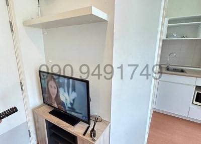 Spacious living room with television and adjoining kitchenette