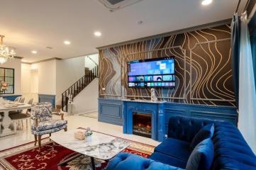 Elegant living room interior with blue velvet sofa, fireplace, and dining area