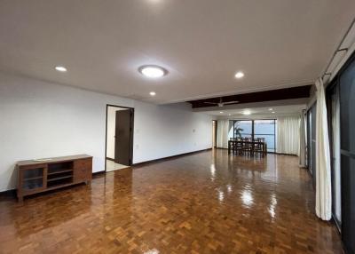 Spacious empty living room with parquet flooring and ample natural light
