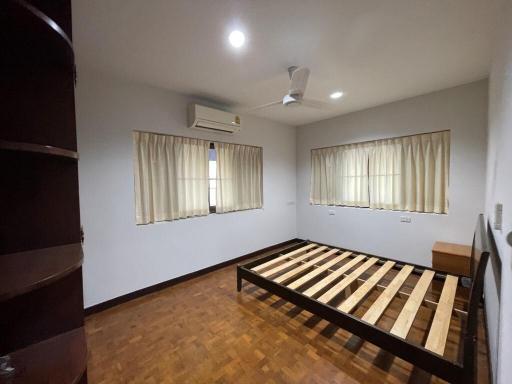 Spacious bedroom with wooden flooring and ample natural light