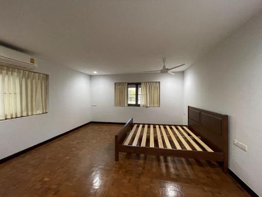 Spacious bedroom with wooden flooring and large windows