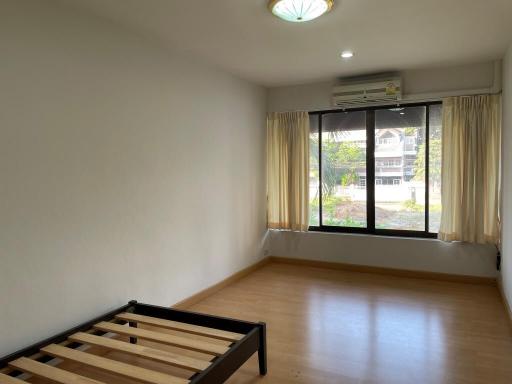 Empty bedroom with large window and wooden flooring