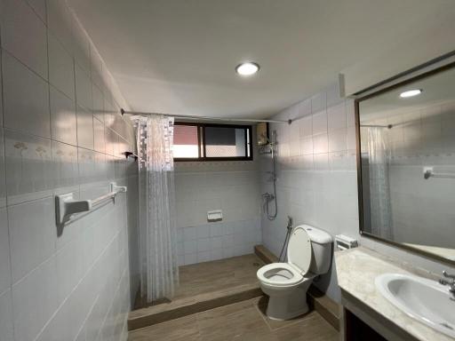 Modern bathroom with shower curtain, toilet, and large vanity mirror