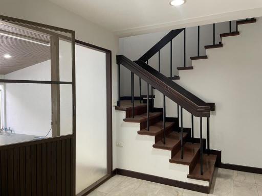 Modern staircase with wooden steps and metal handrails in a well-lit interior space