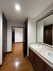 Interior view of a property showing a hallway with wooden flooring, doorways to other rooms, and a bathroom vanity unit