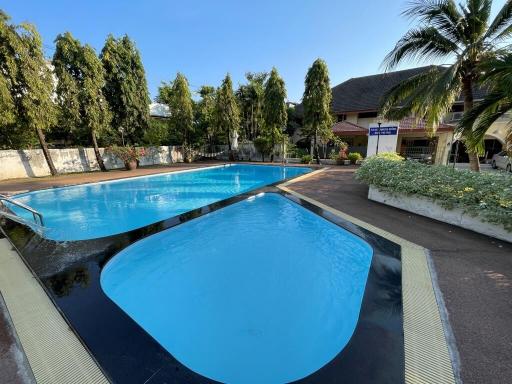 Spacious outdoor swimming pool with surrounding trees and residential buildings