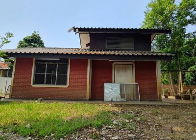 Single-story house with a red brick facade and surrounding greenery