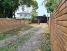 Spacious outdoor area with a gravel driveway and brick wall