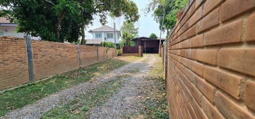 Spacious outdoor area with a gravel driveway and brick wall