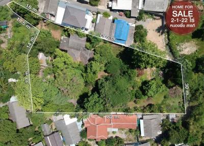 Aerial view of a residential land plot for sale surrounded by buildings and vegetation