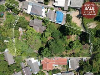 Aerial view of a residential land plot for sale surrounded by buildings and vegetation