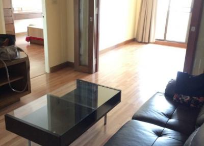 Spacious living room with hardwood floors, large sofa, and glass table